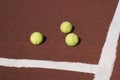 Three tennis balls on brown synthetic court Royalty Free Stock Photo