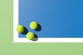 Three tennis balls at the corner of the lines on blue tennis court. 3D rendering. Flat lay overhead view