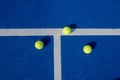three tennis or paddle balls on the blue ground, after a paddle tennis tournament