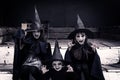 Three terrible witches little girls look at the camera intimidatingly. Halloween concept. Toned