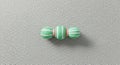 Three textured green and white striped spheres with red accents on a light gray bumpy surface Royalty Free Stock Photo