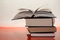 Three thick books on an orange table. A fan from the pages of a book. Open book. Background of intellectual development. Knowledge