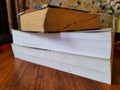 three thick books are stacked one upon another on a wooden table