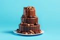 Three-tier chocolate cake with sweets on a blue background close-up.