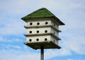 A three tier white wooden bird house with green roof