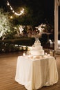 Three-tiered wedding cake decorated with flowers on a table with a tablecloth Royalty Free Stock Photo