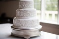 a three-tiered white fondant cake with silver designs