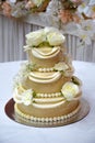 Three tiered white wedding cake decorated with flowers and beads on a table Royalty Free Stock Photo