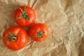 Three tomatoes on crumpled kraft paper background Royalty Free Stock Photo