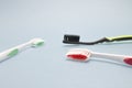 Three tooth brushes on the grey background. Red, black and green toothbrushes. Sanitary hygiene protection, personal care.