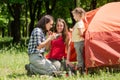 Three tourist females eat near tent outdoors