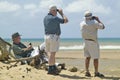 Three tourists with binoculars studing birdlife at Greater St. Lucia Wetland Park World Heritage Site, St. Lucia, South Africa