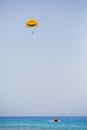 Three tourists flying on a yellow parachute with smiling face on it Royalty Free Stock Photo