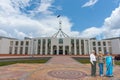 Three tourists of Indian ethnicity standing on indigenous design mosaic pavement in front Parliament House in Canberra