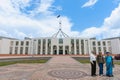 Three tourists of Indian ethnicity standing for photo in forecourt of Australian Parliament building
