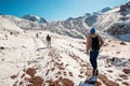 Three tourists on the mountain trail climb the snow top