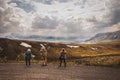 Three tourists taking pictures of distant mountain range from a dirt road in Denali Park Alaska USA