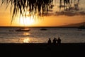 Three tourists watching a beautiful Hawaiian sunset on the beach in Maui Royalty Free Stock Photo