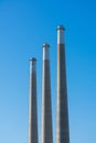 Three towering concrete smoke stacks of decommissioned power plant soaring into blue sky Royalty Free Stock Photo