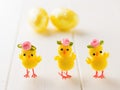 Three toy Chicks and two Easter eggs on a white wooden table. The decoration of the Easter table. Royalty Free Stock Photo