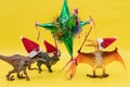 Three toy dinosaurs with Santa Claus hats and a mexican pinata