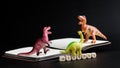 Three toy dinosaurs stand on an open notebook next to the inscription history. The concept of studying history, the Mesozoic era