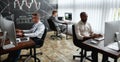 A world for learners. Three traders sitting by desks in front of computer monitors while working in the office