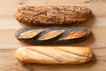 Three traditional baguettes isolated on light wood. Plain, whole wheat and poppy seed. Top view