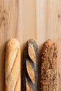 Three traditional baguettes on light wood. Plain, whole wheat and poppy seed. Top view. Space for text Royalty Free Stock Photo