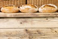 Three traditional loaves of well-baked, cracked bread lie on the wooden counter as the pride of the bakery. Traditional