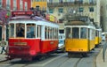 Three Traditional old Red & yellow Lisbon trams on Largo das Portas do Sol blocking traffic.