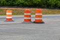 Three traffic barrels in a road construction area, orange safety barricade, asphalt copy space