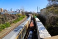 Three trains on the railroad tracks with a rusty iron bridge over the trains surrounded by lush green trees and plants Royalty Free Stock Photo