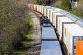 Three trains riding on the railroad tracks surrounded by lush green trees and bare winter trees in Atlanta