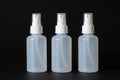 Three translucent plastic spray bottles with white caps on a dark background Royalty Free Stock Photo