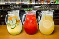 Three transparent jugs with refreshing cold red and yellow lemonade stand on a bar counter. Royalty Free Stock Photo