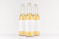 Three transparent longneck beer bottles 500ml with blank white label on white wooden board, mock up.