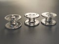 Three transparent plastic sewing machine bobbins. Textile industry. Detail of sewing equipment. Gray background, back lighting Royalty Free Stock Photo