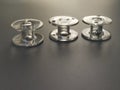 Three transparent plastic sewing machinebobbins. Textile industry. Detail of sewing equipment. Gray background, back lighting. Royalty Free Stock Photo