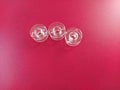 Three transparent plastic sewing machine bobbins. Textile industry. Detail of sewing equipment. Red background Royalty Free Stock Photo