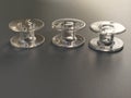 Three transparent plastic sewing machine bobbins. Textile industry. Detail of sewing equipment. Gray background, back lighting Royalty Free Stock Photo