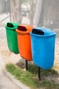 Three trash bin in different colors on a park