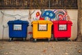 Three trash cans are lined up against a wall with graffiti on it Royalty Free Stock Photo