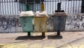 Three trash cans on the pedestrian sidewalk