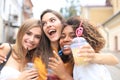 Three trendy cool hipster girls, friends drink cocktail in urban city background
