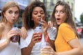 Three trendy cool hipster girls, friends drink cocktail in urban city background