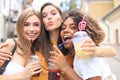 Three trendy cool hipster girls, friends drink cocktail in urban city background.