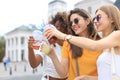 Three trendy cool hipster girls, friends drink cocktail in urban city background.