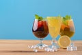 Three tropical mixed drinks with lime and lemon and mint leaves served in different glasses on rustic wooden table. Royalty Free Stock Photo