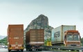 Three trucks passing by in a highway with rock hill in background, parallel commercial transportation Royalty Free Stock Photo